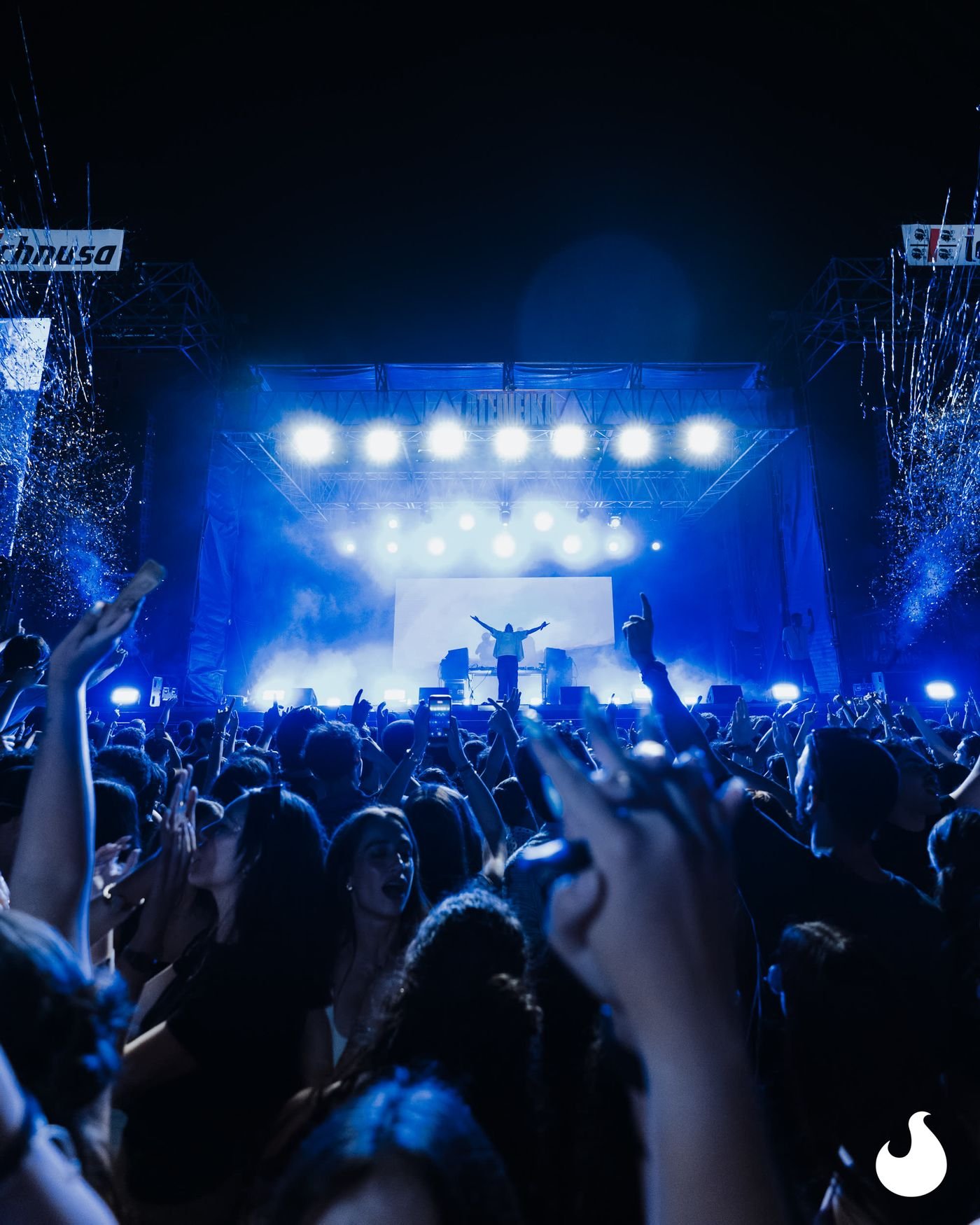 Il palco principale illuminato di blu, visto da dentro la folla.