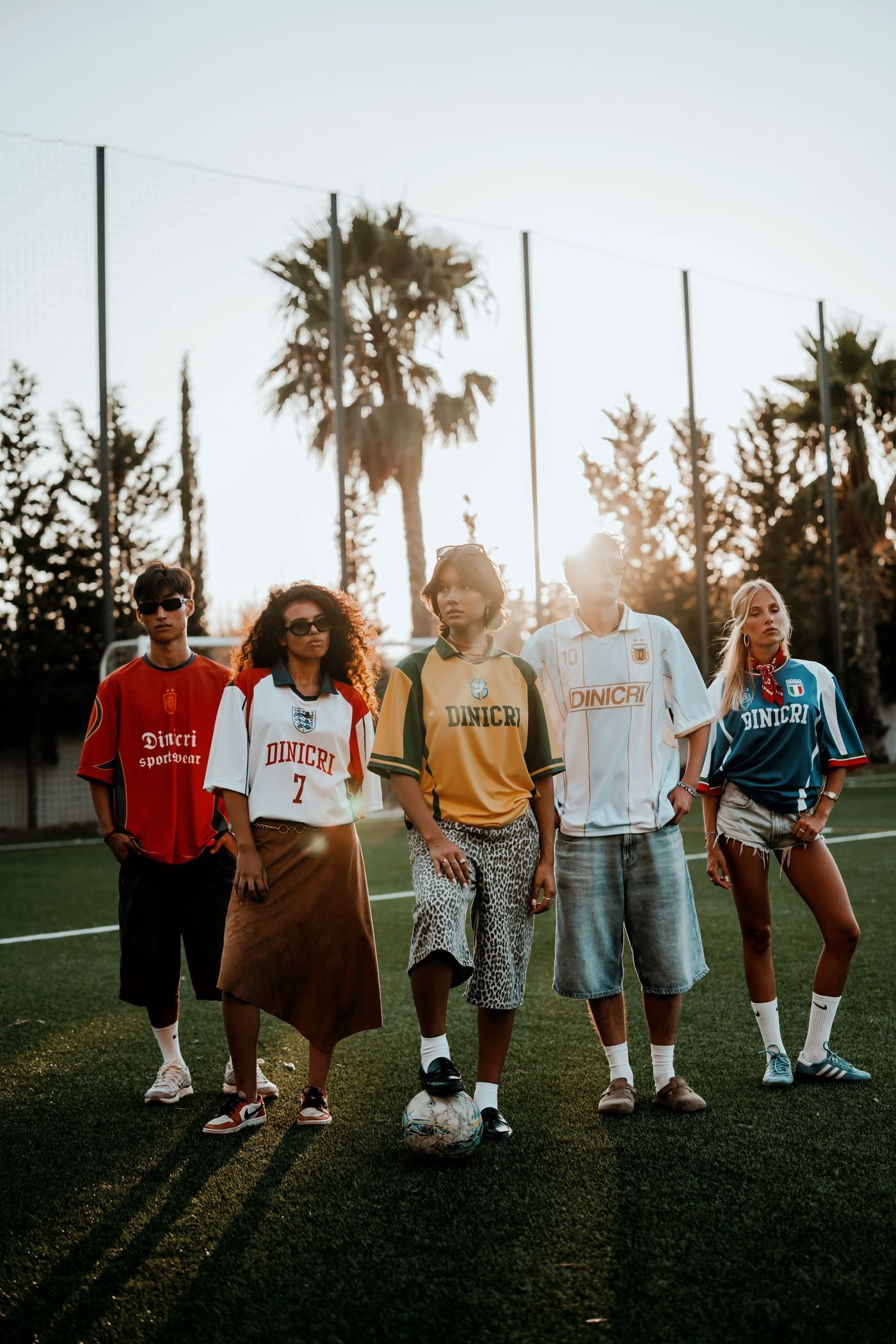 Cinque persone in campo al tramonto, ognuna con la maglia Dinicri di una nazionale diversa.