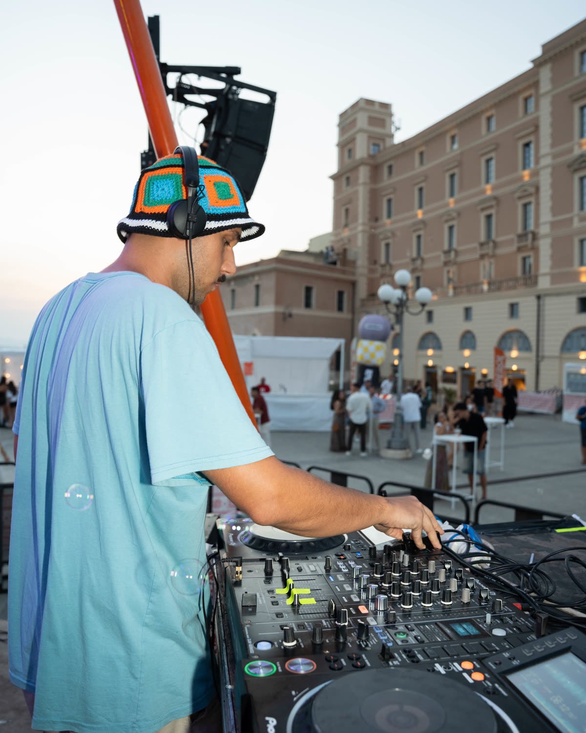 Un dj alla consolle al Bastione con la città alle spalle, ancora giorno.