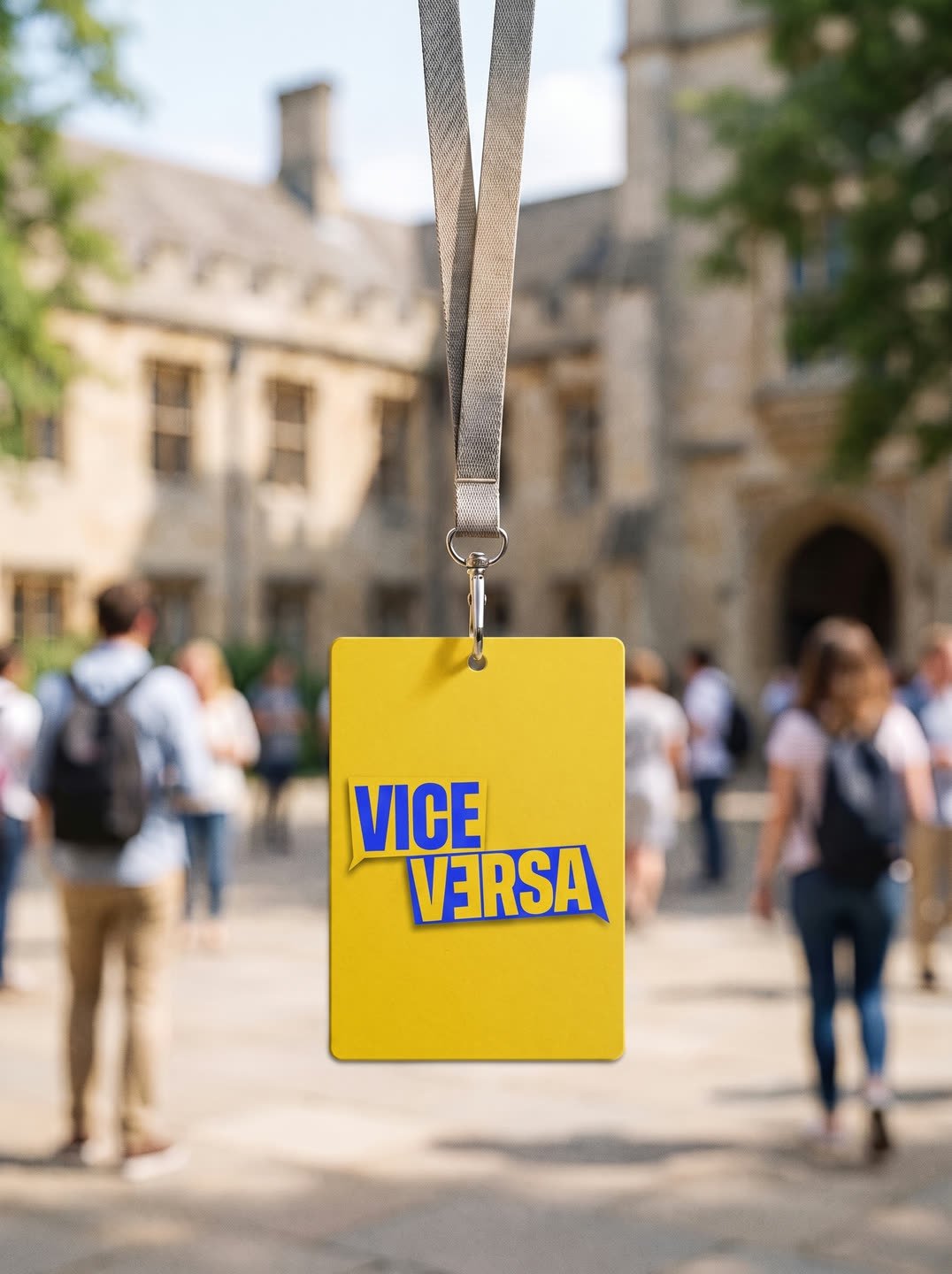 Un accredito giallo con il marchio Viceversa appeso al laccetto, con il campus sfocato dietro.